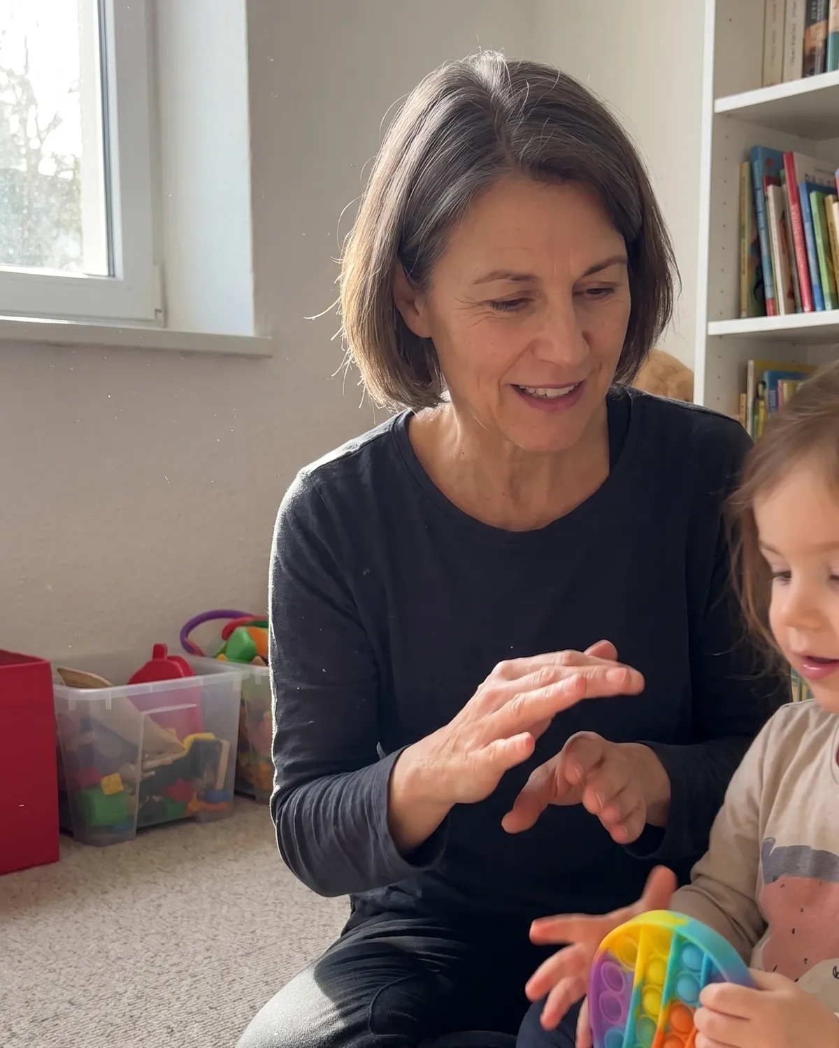 Maren Whitcomb on the floor with a young child during a session